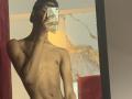 AndyCris, shirtless, wearing a black cap, holding a phone in front of his face, mirror selfie, slim, toned, dark skin, visible nipples, red and white wall in background.