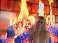 Blonde Dierdre Lorenzano se tient nue devant un mur de briques rougeoyant, ses seins étant légèrement visibles, avec des bûches en feu brûlant derrière elle, avec des flammes bleues et oranges..