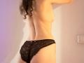 Une prise de vue en contre-plongée des jambes de SweetClaraa, montrant ses cuisses et ses fesses nues, avec sa peau brune et de légères cicatrices visibles. Ses fesses sont partiellement visibles dans le cadre..