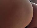 Sloaneswan's ass, close-up, showing textured skin and brownish tan color, with subtle shadowing and soft light highlighting the curvature.