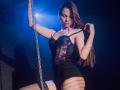 AgataRyili in black lace corset, holding chain, long brown hair, eyes closed, seductive pose, black shorts, thigh garter, blue spotlight, shadow on wall, sexy, curvy, attractive.