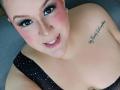 GiiannaMorrys has pink blush, black eyeliner, and a nose ring. She's topless with polka dot lingerie, showing her tits and a tattoo on her right boob.