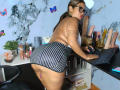 AlixLow with glasses, brown hair in a ponytail, wearing a striped mini-dress, bent over a desk, showing her ass, with a dildo on the right and her pussy exposed.