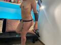 ArianaBlonde is topless with small tits, wearing black lace panties and black heels. She has tattoos on her arm and thigh, with a chain around her waist.