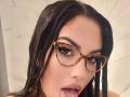 ZoeyMarie has wet brown hair, tortoiseshell glasses, and is sticking her tongue out with saliva on it. Her brown eyes and full pink lips are visible.
