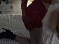 Rozalin's red ruffled shorts, hand on her ass, black high heels, and pale legs kneeling on a white bed with ribbed texture. Her red-gloved hand touches her right cheek.