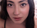 AnnFisher's face, brown eyes, dark eyebrows, long eyelashes, small nose piercing, glossy pink lips, light brown skin, dark brown wavy hair, soft light, slight smile, subtle makeup.
