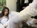 Mettis with long brown hair, white long-sleeve shirt, and white thigh-high socks, legs up, showing her white socks and boots, in a relaxed, slightly surprised pose.