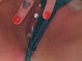 FrenchShanna's pussy with green lace panties, red nail polish, and a heart tattoo on her index finger, featuring a pearl and jewel butt piercing.