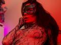Tsukerberg with long black hair, wearing a green mask and black lace bodysuit, red light highlighting her tits and nipples, finger near mouth, looking seductive.