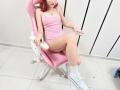 JuliannaMoor with red hair, pink tank top, and white sneakers, sitting on a pink chair, holding a white dildo, showing her bare ass and legs.