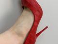 Tattiya's foot in a red, croc-embossed stiletto, showing a pale, slightly veined ankle with a pointed heel. The shoe is on her right foot.