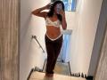 SofiaPassionne with curly hair, wearing a white lace bra and brown pants, showing her tits and small ass, taking a mirror selfie in a stairwell.