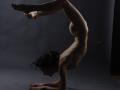 KamiLove is doing a nude, flexible pose, arching backwards with her tits and ass in the air, hands on the ground, legs raised, dark hair, and a slender, toned body.