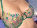 AuroraBenson's tits in a green, sheer bra with colorful floral embroidery. Her breasts are medium-sized, and the bra has a small heart-shaped jewel on the right cup.