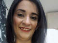 MaraRoberttss ha i capelli castano scuro, il rossetto rosso e un sorriso che mostra i suoi denti bianchi. Ha le sopracciglia nere, la pelle chiara e indossa un trucco leggero..
