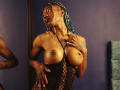 DaniaMarcell, dark-skinned with braids, wearing black lace, exposes her large, round tits. She's touching her chest, looking up, with a gold chain necklace.