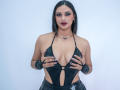 AdalinaVera with black leather halter top, showing her tits with her hands, wearing black leather gloves, dark lipstick, and a necklace against a white background.