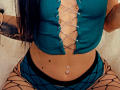 SinReea's teal crop top with lace-up front, exposing her tits, paired with fishnet pants, showing her belly button piercing and a few moles. Her long black hair's visible.
