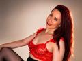 SweettEve with red lace bralette, showing her tits, smiling, red lipstick, long red hair, black stockings, sitting, looking at camera, sexy, confident, attractive.