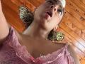 NatalyBlonder has leopard print earrings, pink lace top, and pouty open mouth, looking up with brown hair and fair skin, wearing a pink bow in the lace.