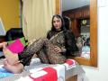 AfroditaHan with long black hair, wearing a see-through lace outfit, sitting on a bed with her feet up, showing her soles. Reflection in a wooden mirror.