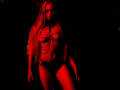 MiaMeowa with long blonde hair, wearing a red-lit chain top and black panties, standing in dark, red-tinged light, showing her toned abs and small, firm tits.