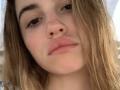 PeacHub69 has a cute, pale face with light brown, wavy hair, brown eyes, and pink, slightly parted lips. Her nose is small, and she's looking down with a neutral expression.