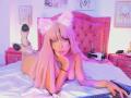 GraceClarke with pink hair, cat ears, and white boots, lying on a bed, naked, with her tits visible, holding a game controller, and her ass up.