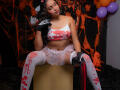 JeimyCampos with large tits, wearing a bloody red and white top, white tulle skirt, white stockings with blood stains, black gloves, holding a red and black flogger.