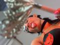 LilithRussoo sticking out her tongue, wearing glasses, black choker, and red-black bikini with red lace, holding a pink brush, in a selfie with a blurred mirror.