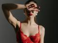 MilagrosEdmisten with red lace bra, covering eyes with hand, red lips, earrings, and slicked-back brown hair, showing off her tits and slim, sexy figure.