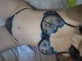 JeneKurz's pale skin and small blue floral lace bra and matching panties show her bare tits and pussy, lying on a bed with a white towel.