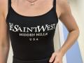 Rorria's black tank top with white text "SANTVEST HIDDEN HILLS USA" shows her small tits and tan skin. She wears a gold necklace with a small pendant.