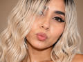 EmilyValk tiene el cabello rubio y ondulado que cubre un ojo, labios rosados y gruesos ligeramente fruncidos, y pestañas negras y gruesas, con una pequeña marca de nacimiento en su mejilla derecha..