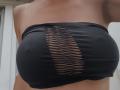 Sloaneswan's big tits in a black strapless top with a central, vertical, ripped pattern revealing her brown skin underneath. The top is tight, highlighting her large breasts.