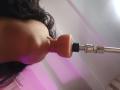 Chili's mouth is around a realistic, flesh-colored dildo with a black base and silver top. Her dark, curly hair is visible on the left side.
