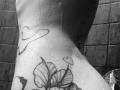 SensualMila's wet, tattooed neck with heart and flower tattoos, droplets of water on pale skin, black and white photo.