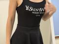 Rorria's black sports tank top and flared skirt, showing her tits, with a white logo text and a slightly blurred hand in the right.