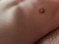 O peito de MaryPele, com um pequeno mamilo rosa no lado esquerdo, exibe um tronco plano, ligeiramente musculoso e pele clara. Não há seios ou genitais visíveis..