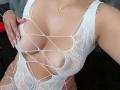 LailaCastillo's white, net-like, crotchless lingerie exposes her tits through large, diamond-shaped cutouts. She has pink nails, a cross necklace, and a tattoo on her right arm.