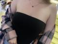 Nesie's bare shoulders and black strapless top, with a pink and black plaid shirt slipping off, showing a delicate necklace and pale skin. Boobs covered by the top.