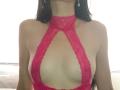 IvannaSinn wearing a red lace halter dress with a deep cut-out showing her bare tits, her long dark hair down, wearing dangling earrings.