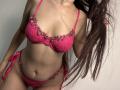 Tisia's pink bra strap and upper chest are visible, with her dark hair partially shown above a large gray block covering her lower face and body.