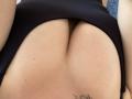 Olieri's ass, shown from behind, with black fabric pulled up to reveal a cleft and small tattoo just above the butt. Olieri's skin is light and smooth.