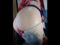 Madiy69's ass in tight blue straps, pink dildo partially in, white thigh-highs, tattoo of a crowned woman on right thigh. Pale skin, red hair. Bedroom.