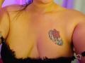 I seni nudi di MichellMonet, con un tatuaggio di una rosa rossa e foglie verdi sul lato destro del petto. Indossa pizzo nero. La sua pelle è abbronzata..