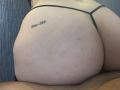 Nella foto, il sedere di BBWCouplehard, con un tatuaggio visibile nella parte superiore destra, è al centro dell'immagine. Indossa uno slip nero e nella parte inferiore si vede una gamba maschile pelosa..
