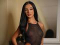 DeniseDevilles with long black hair, wearing a sheer black top, showing her small, perky tits. She's standing with a confident, sexy expression.