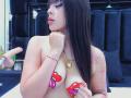 AlisonTatcher has pale skin, long black hair, and is topless with red heart pasties over her tits. She's holding her chin, wearing a gold heart necklace, and has tattoos.
